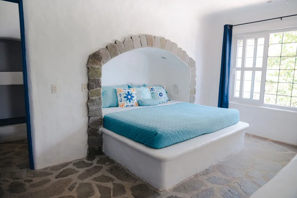 Cama turquesa bajo un arco de piedra.