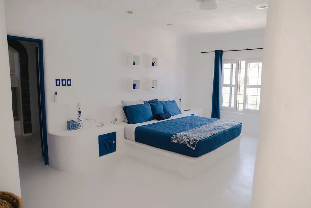 Cama azul en una habitación de paredes blancas.